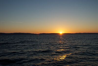 View of a sunrise over land seen from water